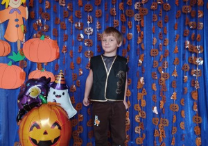 Dziecko pozuje na tle dyniowej dekoracji