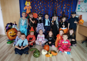 Dzieci pozują na tle dyniowej dekoracji