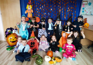 Dzieci pozują na tle dyniowej dekoracji