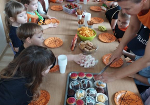 Dzieci siedzą przy stole i spożywają posiłek