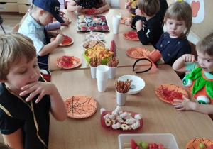 Dzieci siedzą przy stole i spożywają posiłek