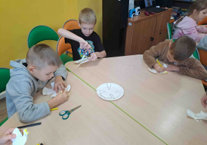 Dzieci wycinają z talerzyków kształt orła