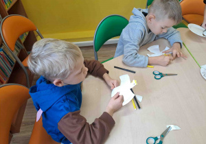 Dzieci wycinają z talerzyków kształt orła