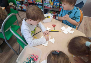 Dzieci wycinają z talerzyków kształt orła