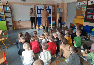 Dzieci siedzą na dywanie i oglądają prezentację na temat praw dziecka