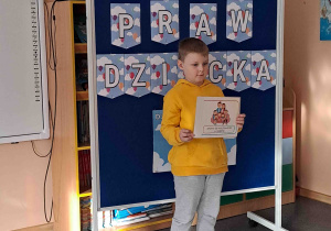 Chłopiec wypowiada się na temat ilustracji trzymanej w rączkach