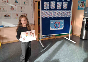 Dziewczynka wypowiada się na temat ilustracji trzymanej w rączkach