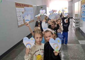 Dzieci na korytarzu szkolnym pokazują wykonane serduszka