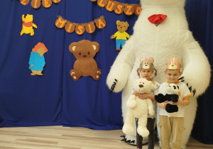 Dzieci stoją przed białym misiem