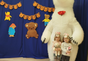 Dziewczynki stoją przed białym misiem