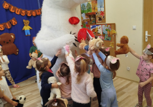 Dzieci przytulają białego misia