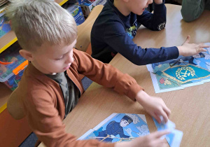 Dzieci przy stoliczkach układają puzzle z wizerunkiem górnika
