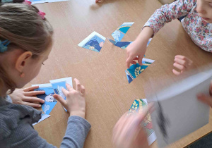 Dzieci przy stoliczkach układają puzzle z wizerunkiem górnika