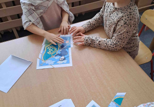 Dzieci przy stoliczkach układają puzzle z wizerunkiem górnika