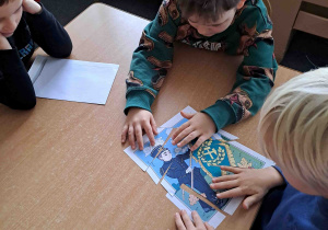 Dzieci przy stoliczkach układają puzzle z wizerunkiem górnika