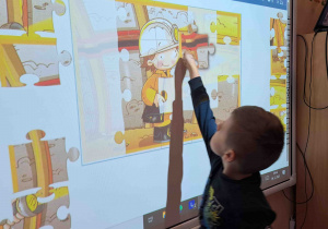 Dzieci wykonują ćwiczenia postrzegania wzrokowego na tablicy multimedialnej