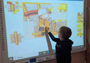 Dzieci wykonują ćwiczenia postrzegania wzrokowego na tablicy multimedialnej