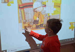 Dzieci wykonują ćwiczenia postrzegania wzrokowego na tablicy multimedialnej