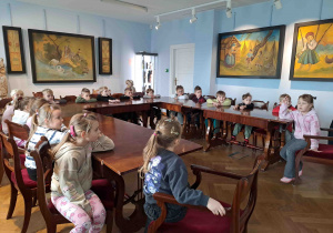 Dzieci w muzeum słuchają opowiadania pani przewodnik