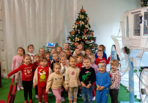 Dzieci pozują do zdjęcia na tle choinki