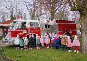 Dzieci pozują do zdjęcia na tle amerykańskiego wozu strażackiego