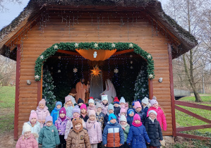 Dzieci stoją przed Szopką Bożonarodzeniową