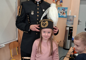 Dziecko w czapce czako pozuje wspólnie z górnikiem do zdjęcia.