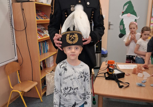 Dziecko w czapce czako pozuje wspólnie z górnikiem do zdjęcia.