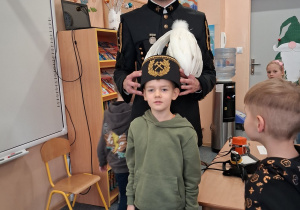 Dziecko w czapce czako pozuje wspólnie z górnikiem do zdjęcia.