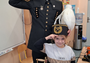 Dziecko w czapce czako pozuje wspólnie z górnikiem do zdjęcia.