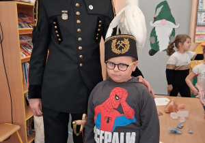 Dziecko w czapce czako pozuje wspólnie z górnikiem do zdjęcia.