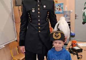 Dziecko w czapce czako pozuje wspólnie z górnikiem do zdjęcia.