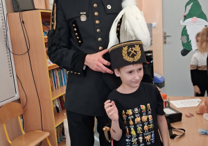 Dziecko w czapce czako pozuje wspólnie z górnikiem do zdjęcia.