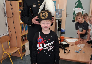 Dziecko w czapce czako pozuje wspólnie z górnikiem do zdjęcia.