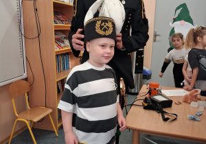 Dziecko w czapce czako pozuje wspólnie z górnikiem do zdjęcia.