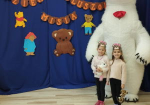 Dziewczynki stoją przed białym misiem