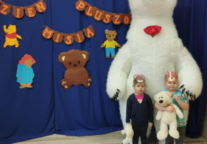 Dzieci stoją przed białym misiem