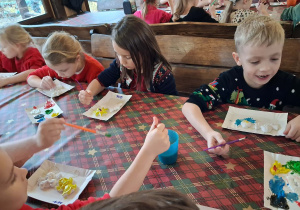 Dzieci malują aniołki farbami na warsztach plastycznych.