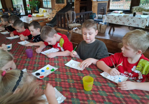 Dzieci malują aniołki farbami na warsztach plastycznych.