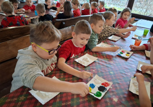 Dzieci malują aniołki farbami na warsztach plastycznych.
