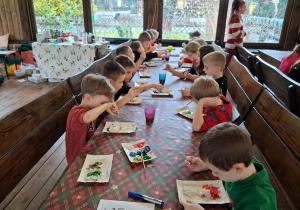 Dzieci malują aniołki farbami na warsztach plastycznych.