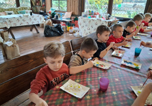 Dzieci malują aniołki farbami na warsztach plastycznych.