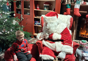 Dzieci siadają obok Świętego Mikołaja chwilkę rozmawiają a na zakończenie Mikołaj wręcza prezent dziecku.