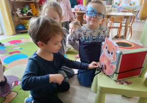 Chłopiec nawleka żołędzie na sznurek i wykonuje ćwiczenia artykulacyjne