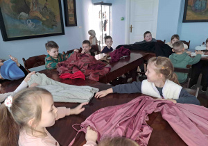 Dzieci oglądają elementy ubioru dworskiego