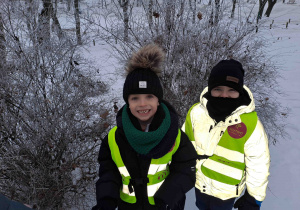 Dzieci w parku oglądają ośnieżone krzewy
