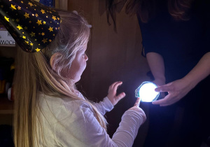 Dziewczynka wskazuje na obrazek podświetlony latarką