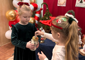 Dziewczynka wkłada pieniądze do słoika