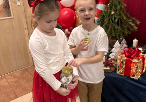 Chłopiec je pierniczka, wskazuje palcem na słoik