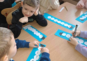 Dzieci podpisują bałwanki swoimi imionami